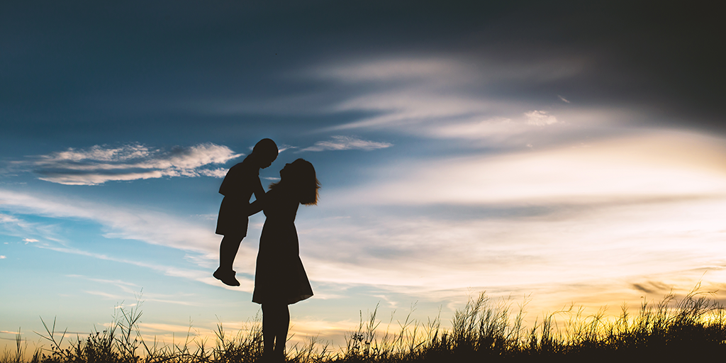 silhouette-of-mother-playing-with-her-son-in-the-meadow