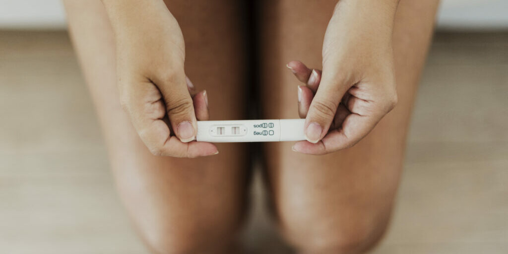 top-view-hands-holding-positive-pregnancy-test